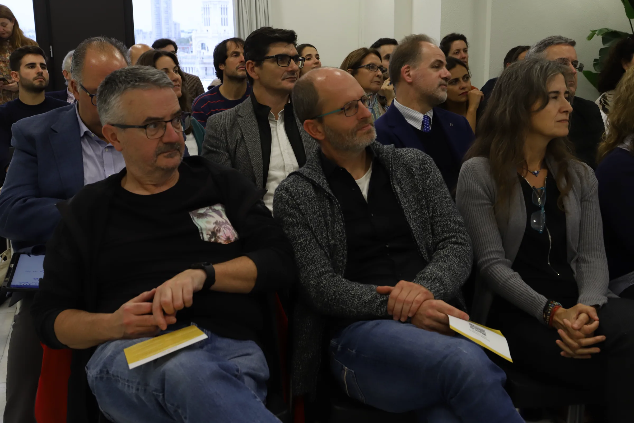 Audience at the conference holding the yellow printed programmes